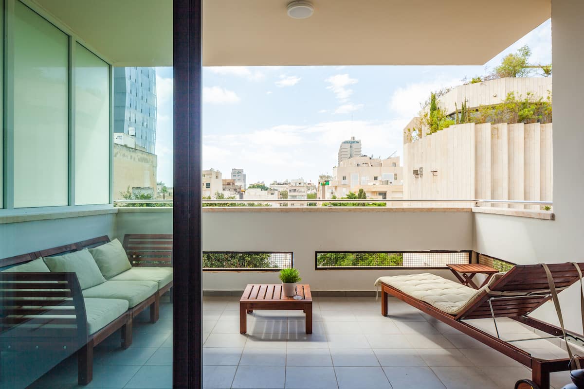 A balcony with a sofa, a small table with a plant, and a daybed.