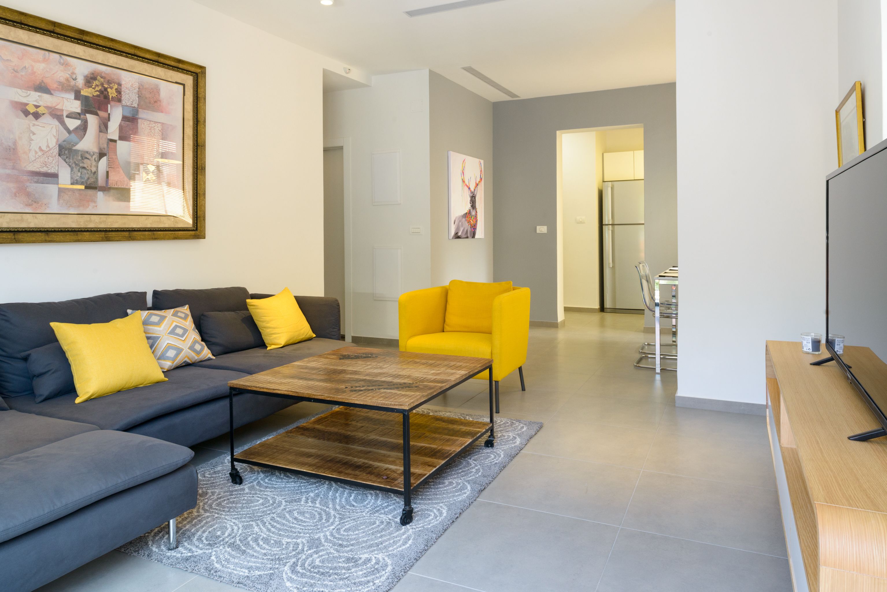 A modern living room with a grey sofa, yellow armchair, and a coffee table.