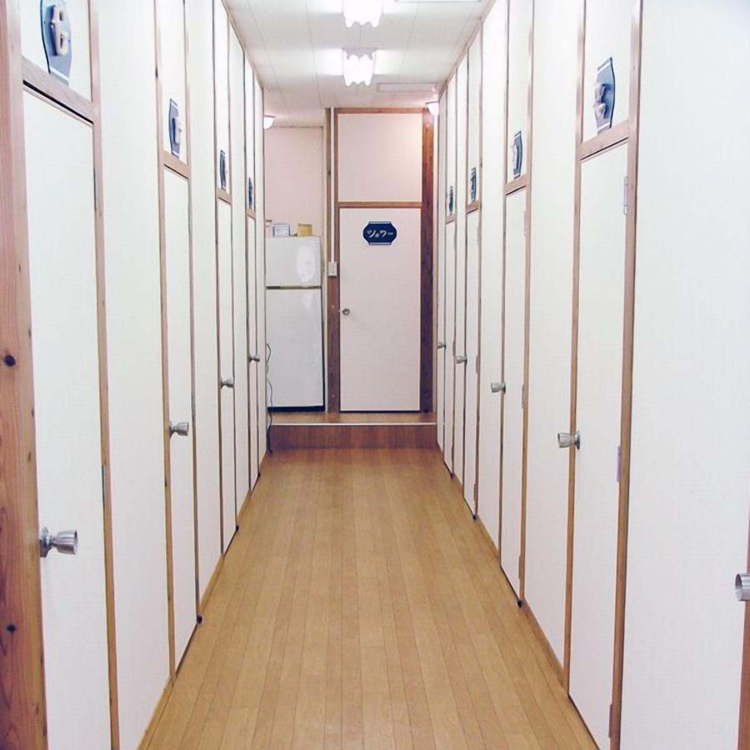 Um corredor com armários, um frigorífico e uma porta com um aviso.