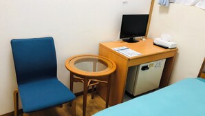 A room with a bed, a desk with a computer, a chair, and a small refrigerator.