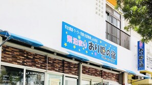 A building with a blue sign, a bench, and potted plants outside.