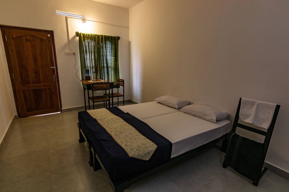 Un dormitorio con una cama, una silla, una mesa y un escritorio.
