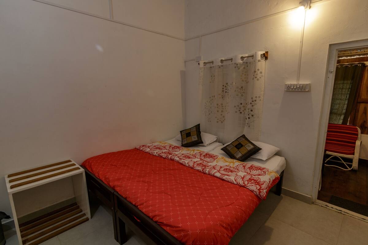 Un dormitorio con cama, mesita de noche, cortina de ducha y puerta que da a otra habitación.