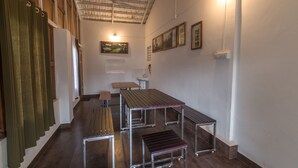 A spacious room with a high ceiling, wooden benches, and tables arranged for dining. - Whispering Willows (Ootacamund)