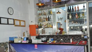 A bar area with shelves of bottles and glasses, a clock, framed certificates, and a payment terminal. - New Season Riverside Hotel (Phnom Penh)