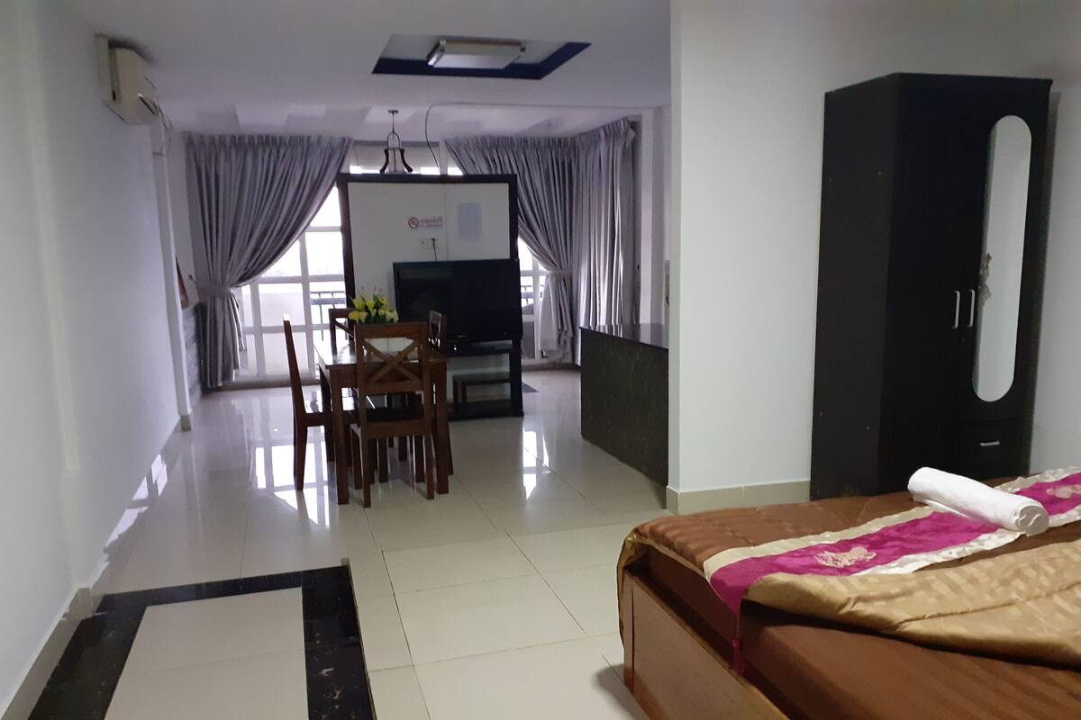 Una habitación de hotel con una cama, un escritorio, una silla, un televisor y un armario.