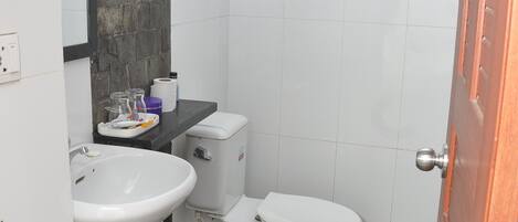 A bathroom with a stone-tiled floor, a white sink, a toilet, and a mirror.
