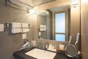 Un baño moderno con un espejo grande, toalleros, un lavamanos y artículos de aseo.