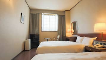 A hotel room with two beds, a desk, a chair, a TV, and a lamp.