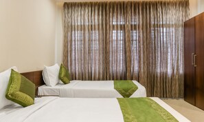 A hotel room with two beds, a wooden wardrobe, and a curtain with vertical lines. - Treebo Casino (Kozhikode)