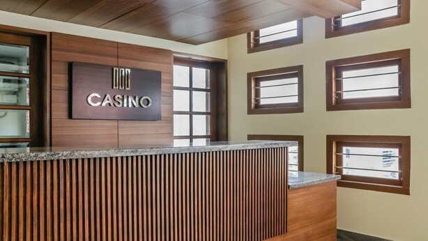 A reception desk with a 'CASINO' sign, wooden paneling, and multiple windows. - Treebo Casino (Kozhikode)