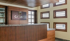 A reception desk with a 'CASINO' sign, wooden paneling, and multiple windows. - Treebo Casino (Kozhikode)