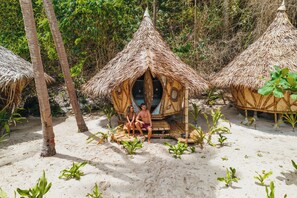 A beach setting with thatched-roof huts and palm trees. - DRYFT Darocotan Island (El Nido)