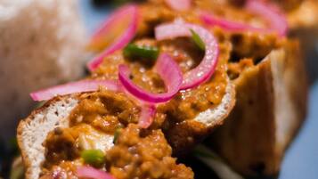 A plate with sliced meat topped with red onion rings, accompanied by a side of white rice.