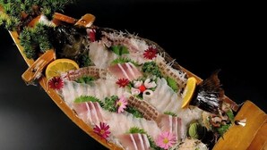 Eine Sushi-Platte mit verschiedenen Fischsorten und Beilagen.