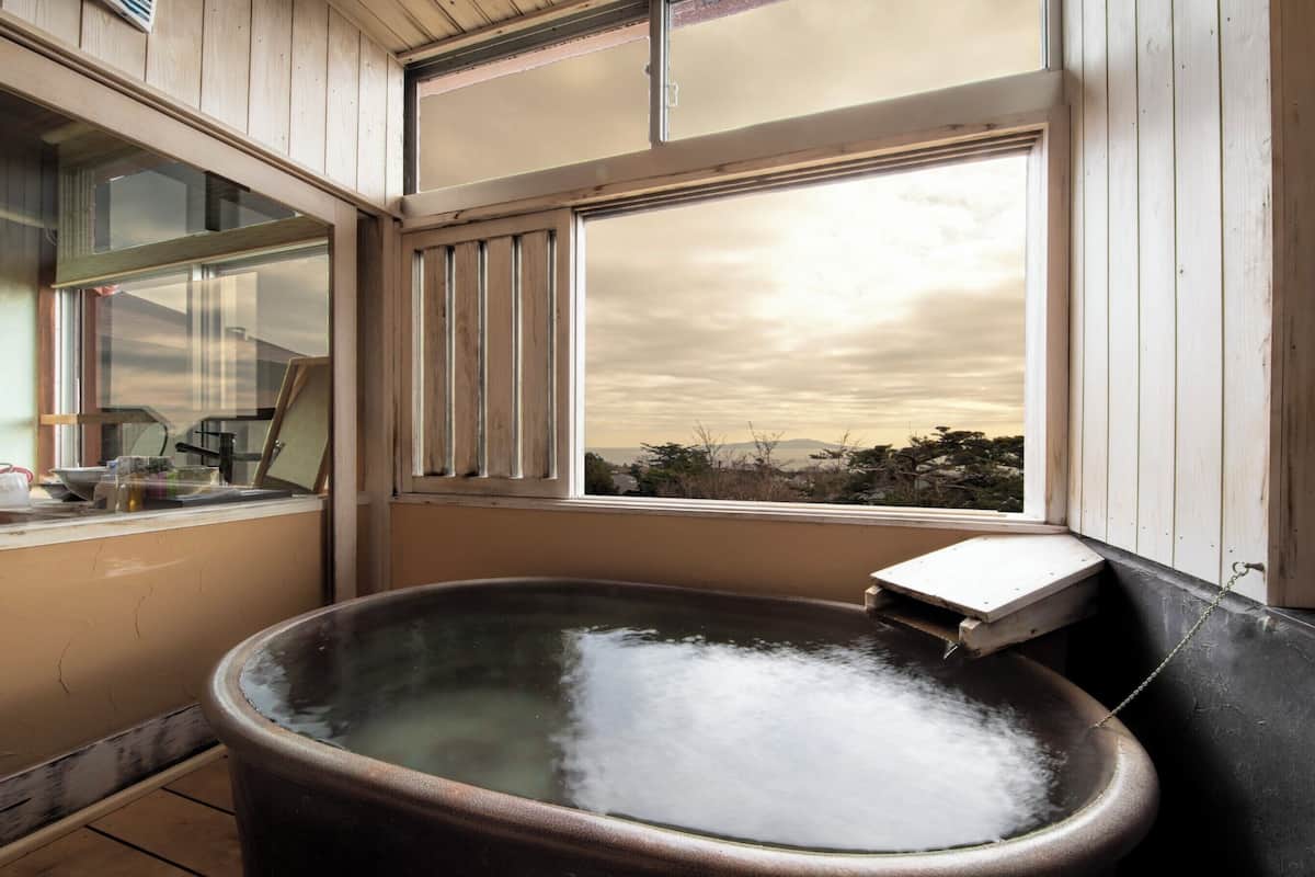 Une salle de bain rustique avec une grande baignoire, des murs en bois et une fenêtre donnant sur un paysage.