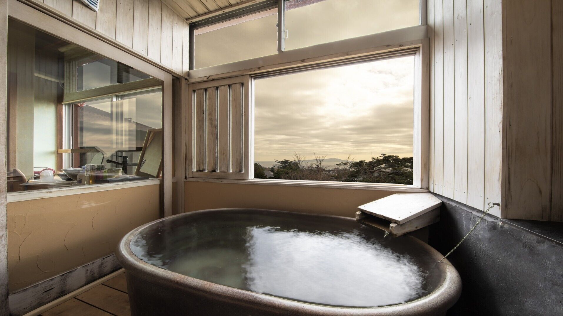 Ein rustikales Badezimmer mit einer großen Badewanne, Holzwänden und einem Fenster mit Blick auf eine Landschaft.