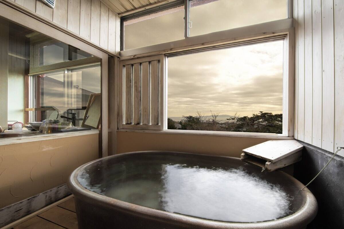 Une salle de bain rustique avec une grande baignoire, des murs en bois et une fenêtre donnant sur un paysage.