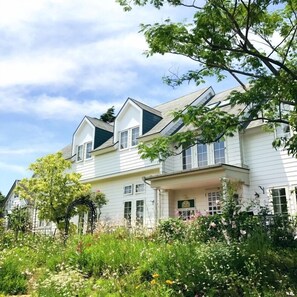A two-story house with a porch and a garden in front. - Country House Hotel Avonlea (Ito)