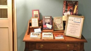 A wooden display table with various books and framed certificates against a blue wall. - Country House Hotel Avonlea (Ito)