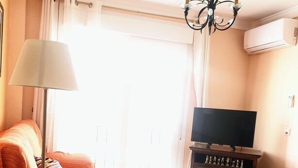 Un salon avec un canapé, une table basse, un téléviseur et un radiateur.