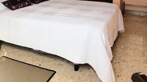 Une chambre à coucher avec un lit, une armoire en bois, un lustre, un tableau encadré et un miroir.