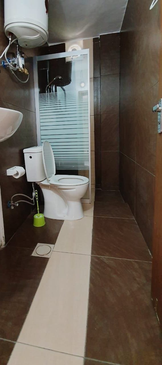 A bathroom with a toilet, a sink, and a shower area.