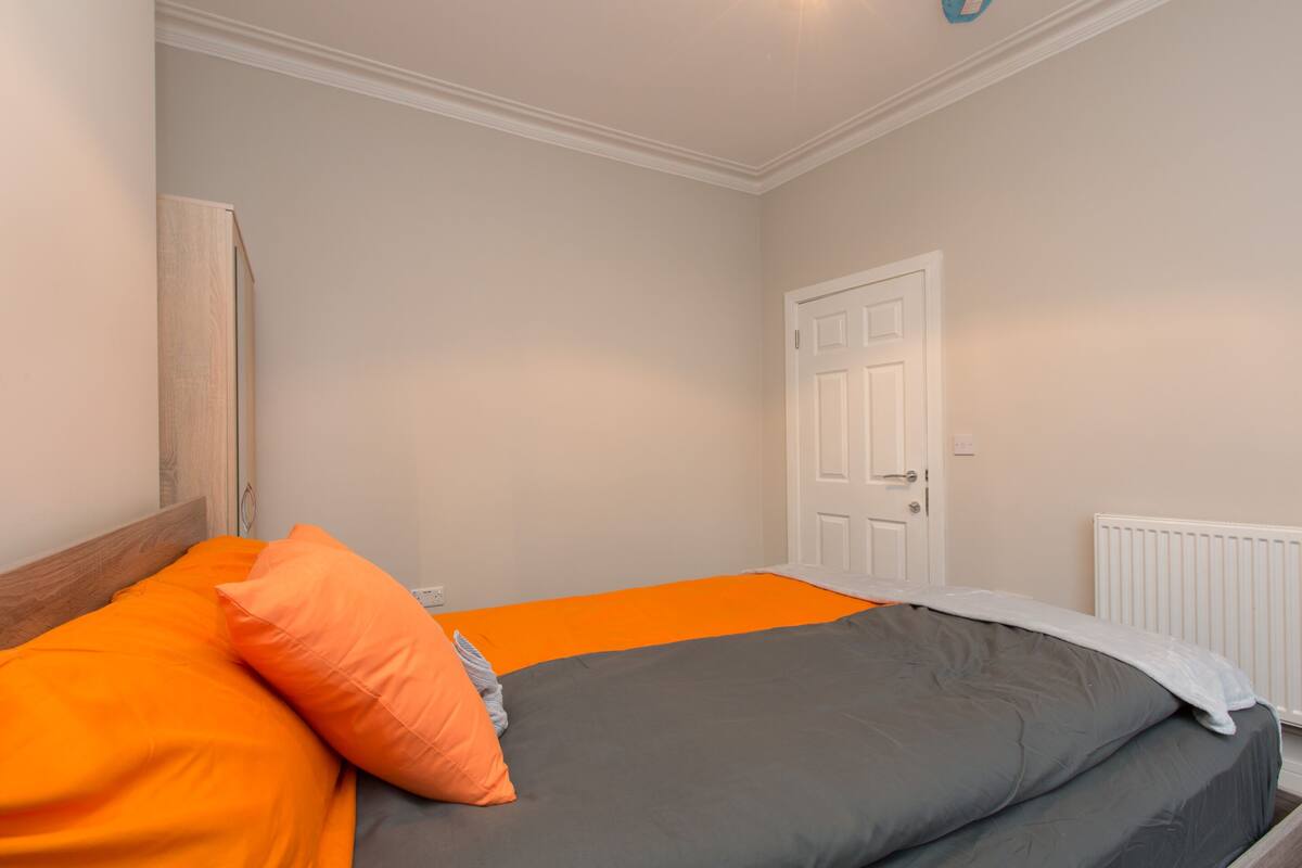 Un dormitorio con cama, puerta y radiador.