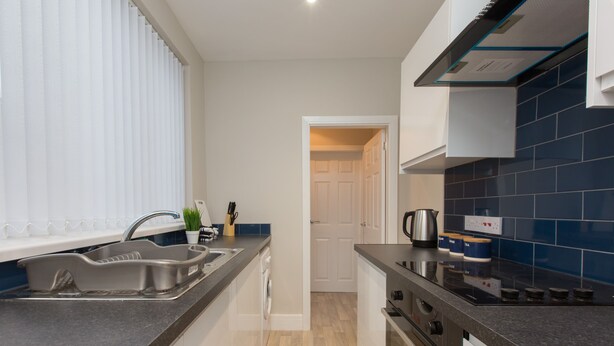 A modern kitchen with a sink, stove, and cabinets. - Townhouse @ Rose Street Stoke (Stoke-on-Trent)