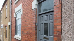 A red brick house with a grey door and white-framed windows. - Townhouse @ Rose Street Stoke (Stoke-on-Trent)
