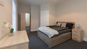 A bedroom with a bed, bedside table, and a nightstand. - Townhouse @ Rose Street Stoke (Stoke-on-Trent)