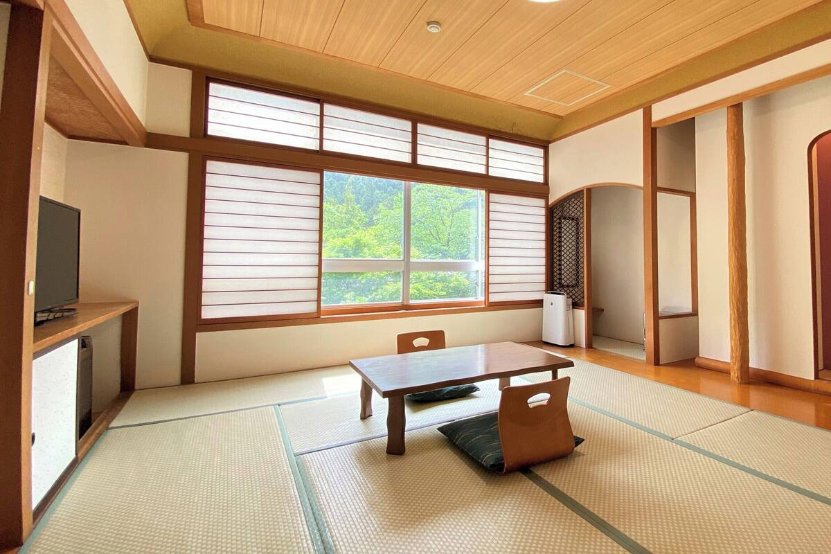 A traditional Japanese room with tatami flooring, a low table, and sliding doors.