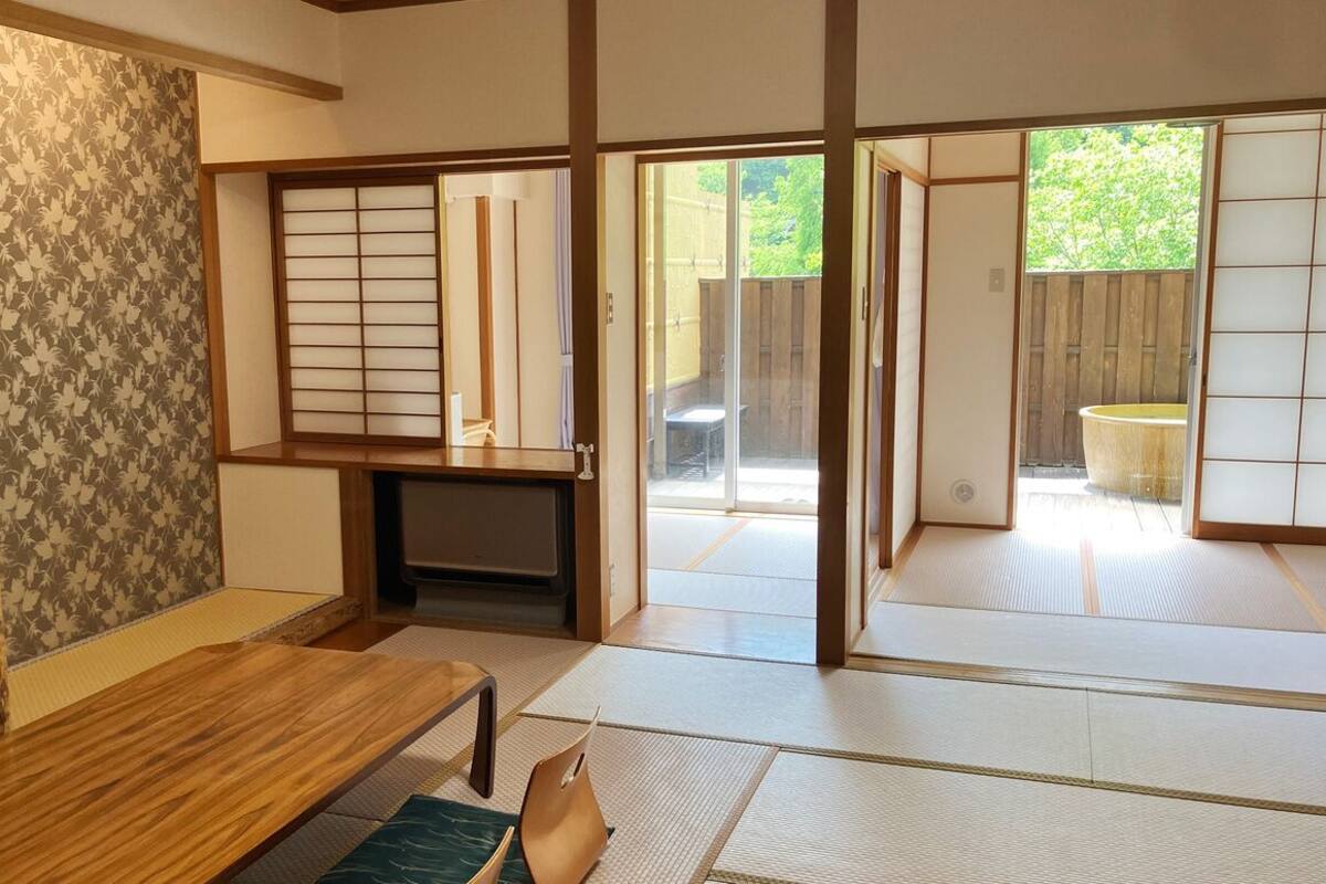 A traditional Japanese room with tatami flooring, sliding doors, a television, and a small table.