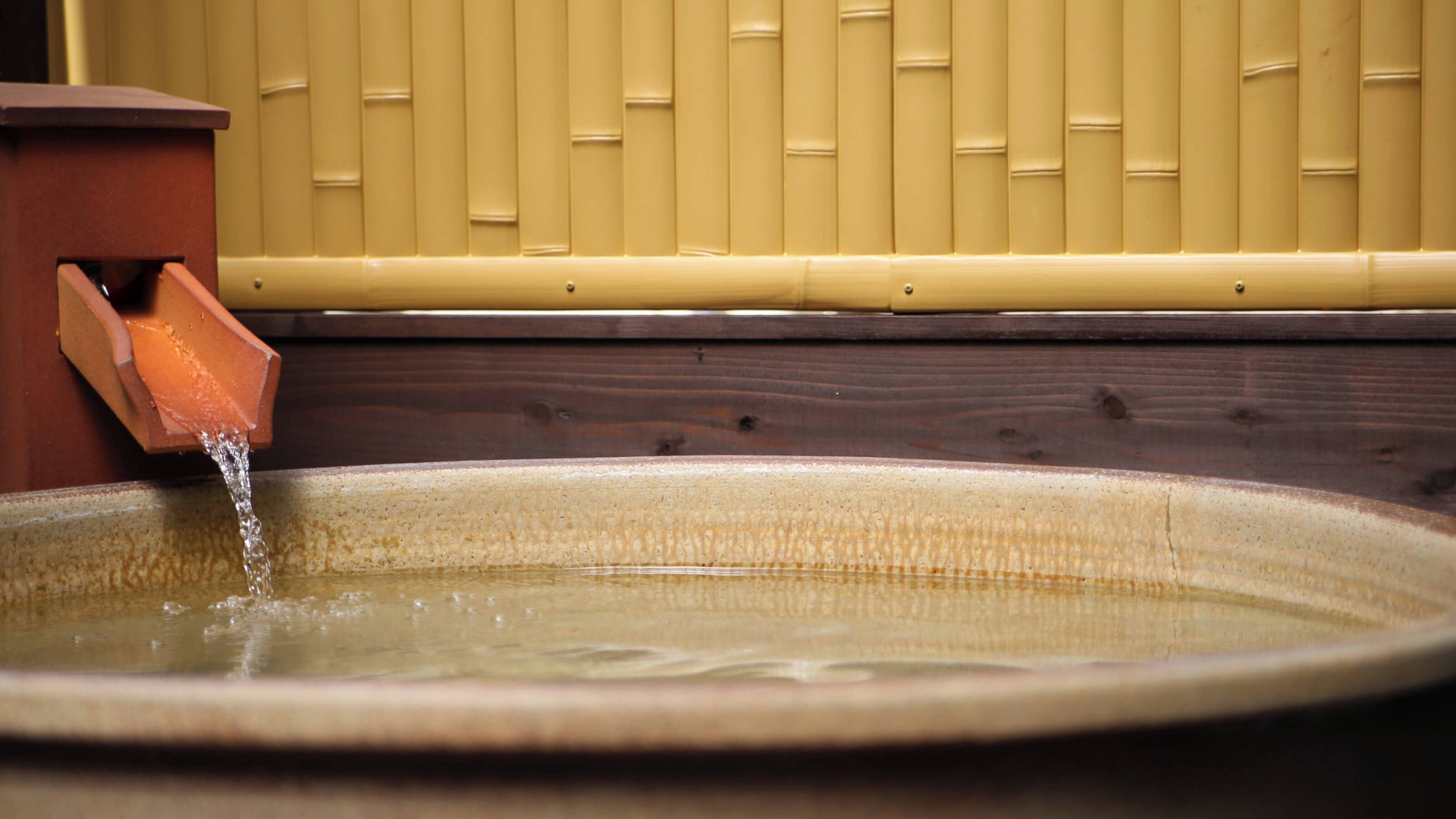 Een keramieken wasbak met water dat uit een terracotta uitloop stroomt.