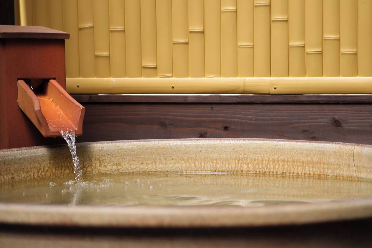 A ceramic basin with water flowing from a terracotta spout.