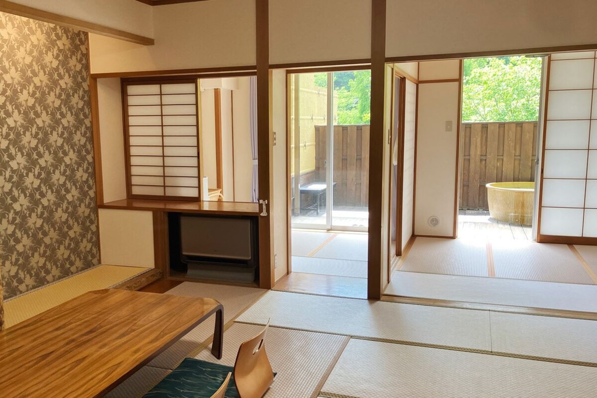A traditional Japanese room with tatami flooring, sliding doors, a television, and a small table.