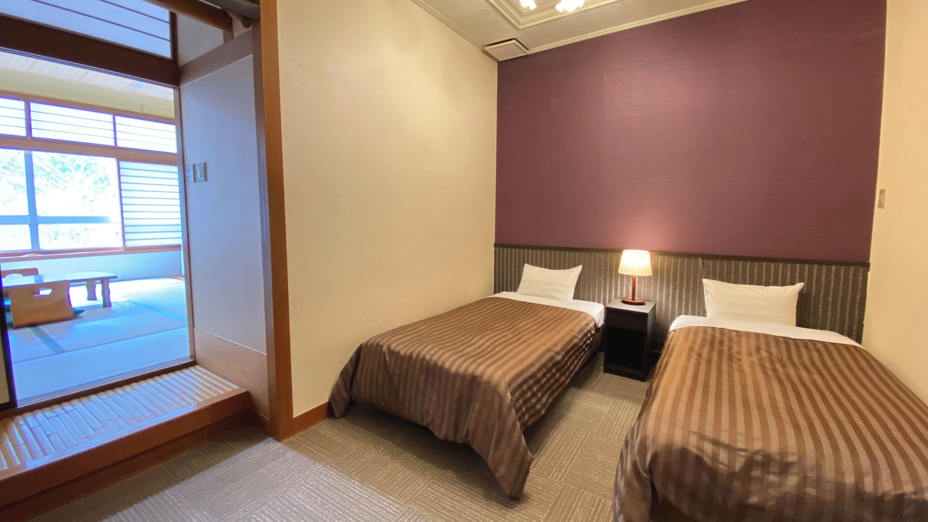 Een hotelkamer met twee bedden, een tafeltje en uitzicht op een terras.