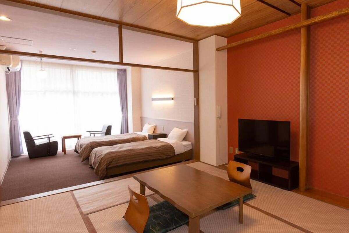 A hotel room with a bed, a TV, a desk, and a chair.