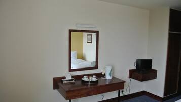 Une chambre d’hôtel équipée d’un bureau en bois, d’un miroir, d’une télévision et d’une machine à café.