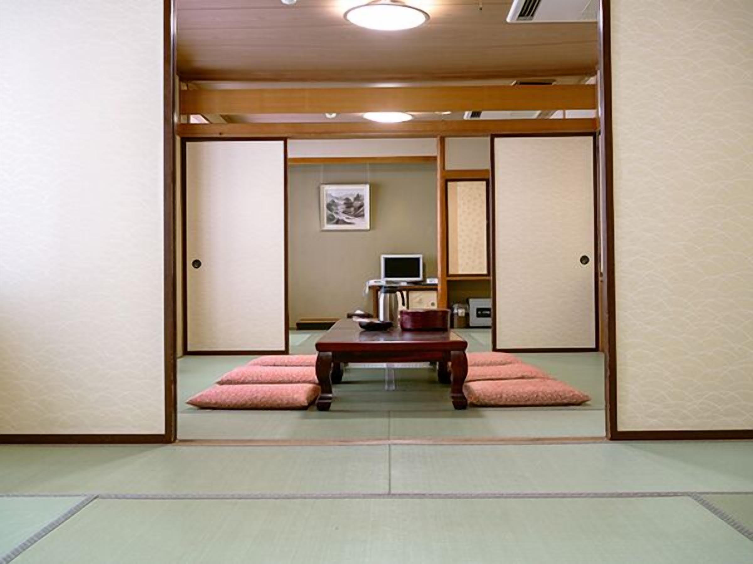 A traditional Japanese room with tatami flooring, a low wooden table, and a television.