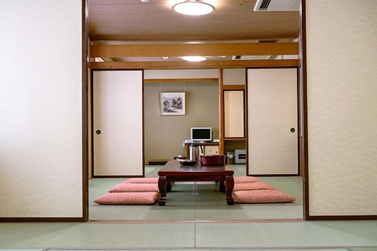 Ein traditioneller japanischer Raum mit Tatami-Bodenbelag, einem niedrigen Holztisch und einem Fernseher.