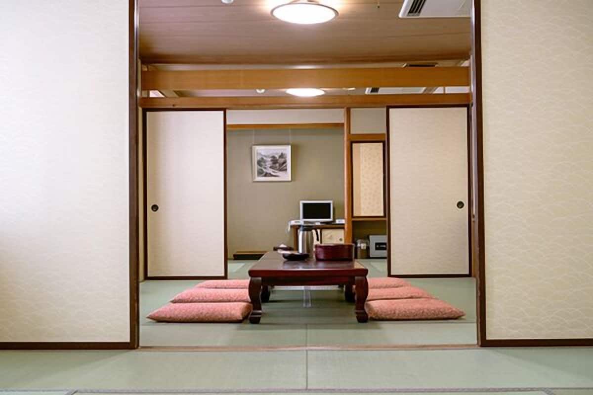 A traditional Japanese room with tatami flooring, a low wooden table, and a television.