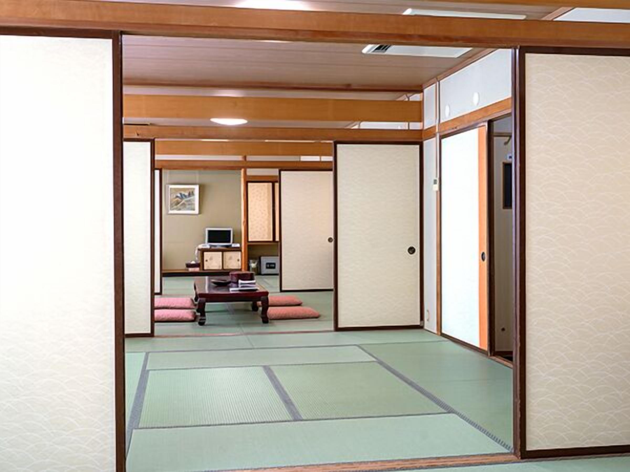 A traditional Japanese room with tatami flooring, sliding doors, and a low table with cushions.