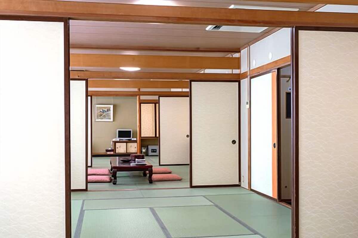 A traditional Japanese room with tatami flooring, sliding doors, and a low table with cushions.