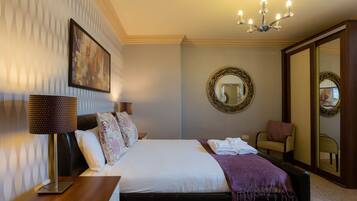 A hotel room with a bed, a bedside lamp, a mirror, and a chair.