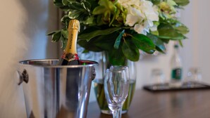 Eine Flasche Champagner in einem Metallkübel, ein Glas und eine Blumenkomposition.