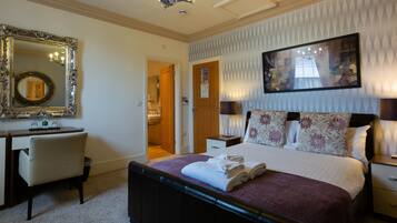 A hotel room with a bed, a desk, a chair, a mirror, and a painting on the wall.