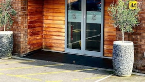 The exterior of The White Swan, featuring a brick facade, a glass entrance with decorative swan motifs, and a parking area with yellow lines. - The White Swan (Gainsborough)