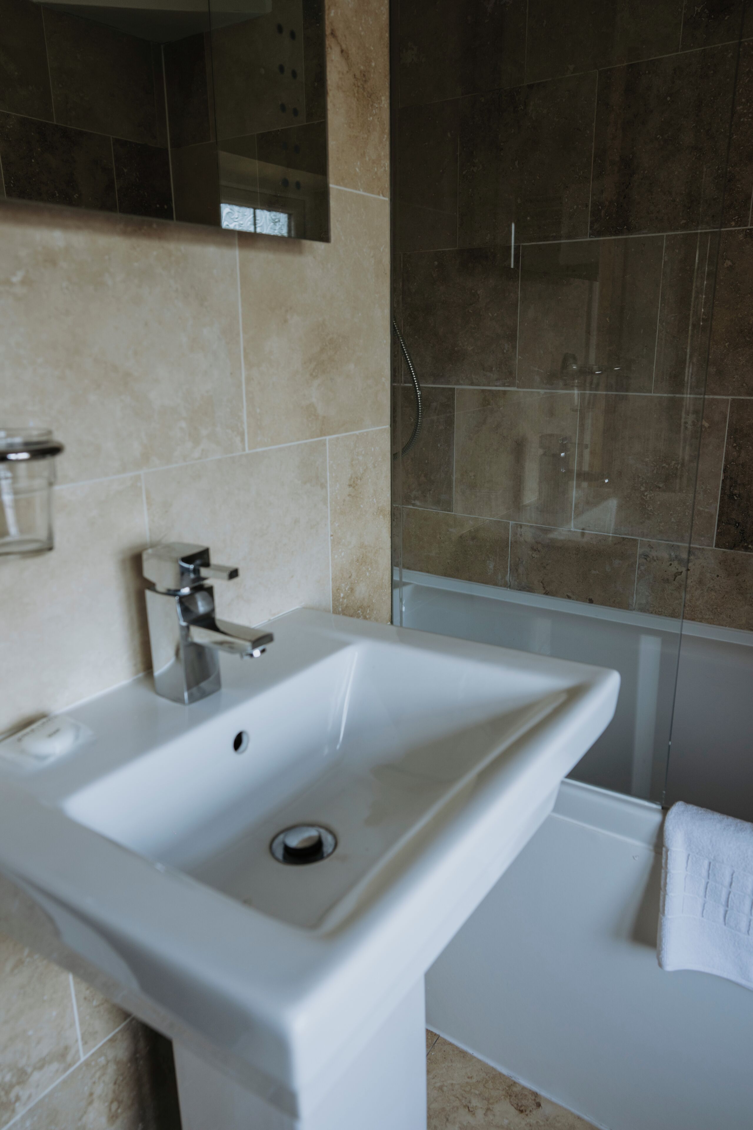 A bathroom with a white sink, a mirror, and a shower area.