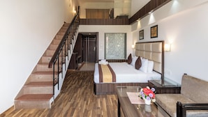 A hotel room with a bed, a sofa, a coffee table, and a staircase. - Shiva Oasis Resort (Behror)